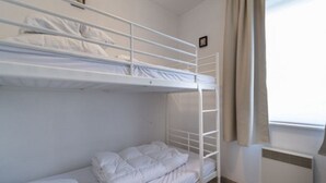 A bunk bed room with white bedding, a window with curtains, and a radiator. - Apartment in Middelkerke Near Beach & Pool (Middelkerke)