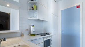 A modern kitchen with white cabinets, a sink, a stove, and a microwave. - Apartment in Middelkerke Near Beach & Pool (Middelkerke)