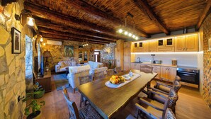 A rustic kitchen with wooden beams, stone walls, and a dining area with a wooden table and chairs.