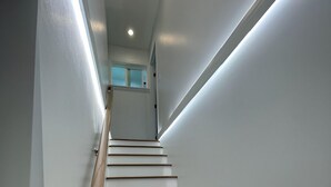Una escalera moderna con escalones de madera y barandilla, que conduce a un rellano con una puerta.