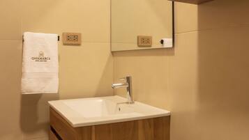 A bathroom with a wooden vanity, a white sink, a mirror, and a towel hanging on the wall.