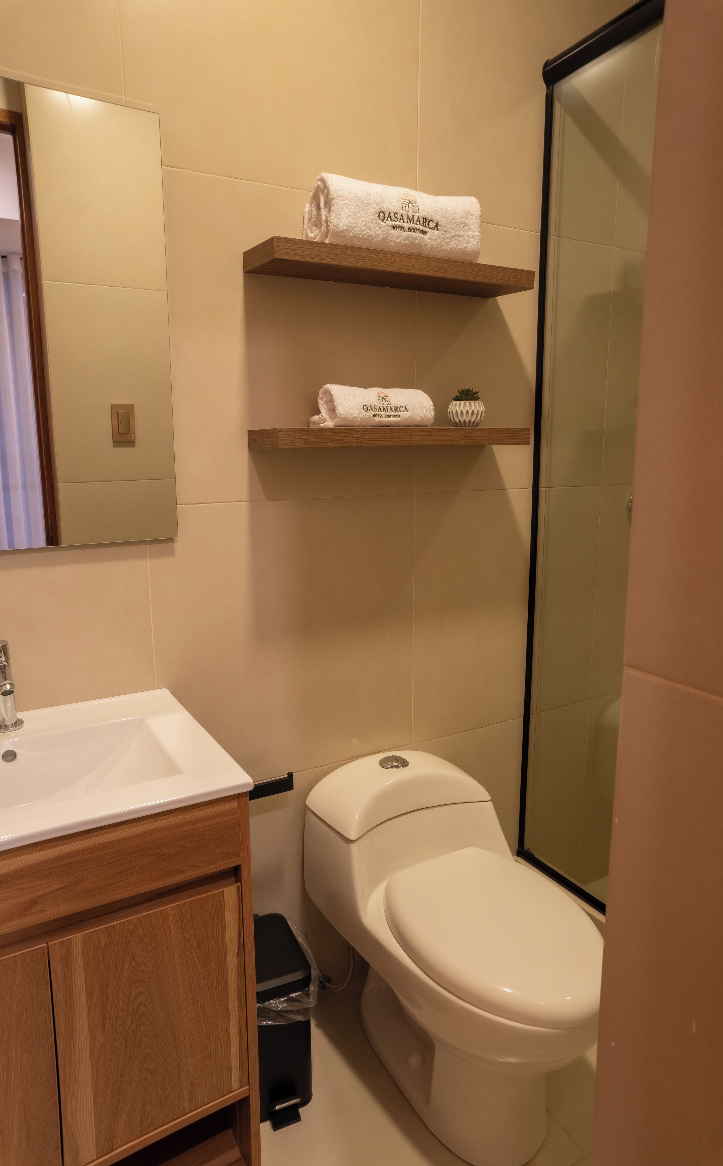 A bathroom with a white sink, wooden cabinet, toilet, and two towel racks with folded towels.