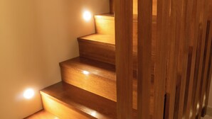 A wooden staircase with illuminated handrails and steps, leading to an upper floor. - Qasamarca Hotel Boutique (Cajamarca)