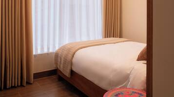 Una habitación de hotel con una cama, una pequeña mesa redonda y una ventana con cortinas.