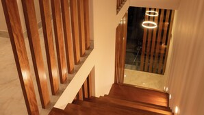 A modern staircase with wooden steps and a glass railing, leading to a higher floor. - Qasamarca Hotel Boutique (Cajamarca)