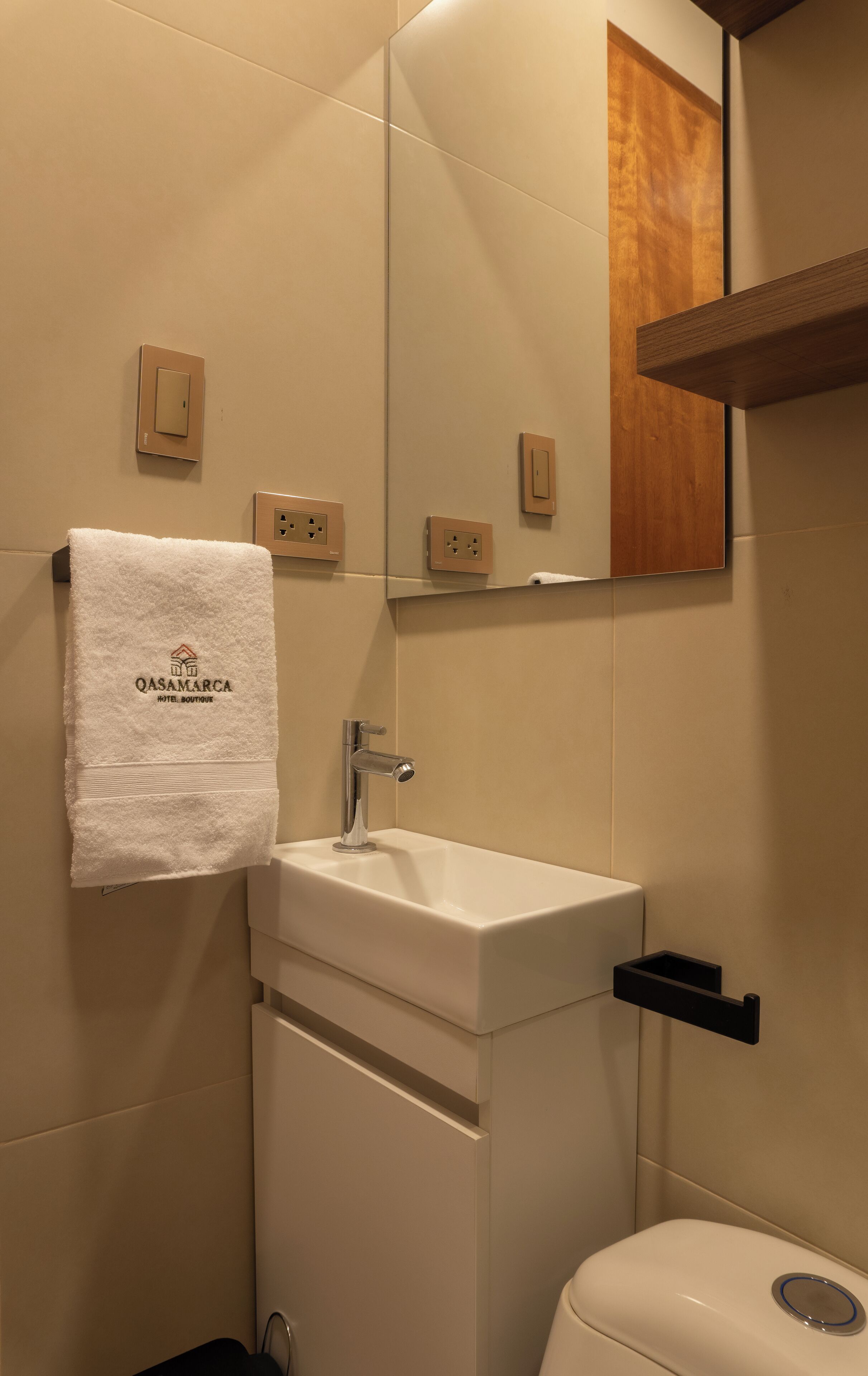 Une salle de bain avec un lavabo blanc, une serviette accrochée au mur et un miroir au-dessus du lavabo.