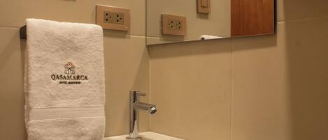 A bathroom with a white sink, a towel hanging on the wall, and a mirror above the sink.