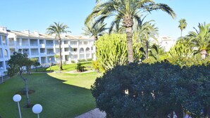 A hotel with a courtyard featuring palm trees, a well-maintained lawn, and a brick pathway. - Anacasa San Fernando MET Oliva Nova AP611 (Oliva)