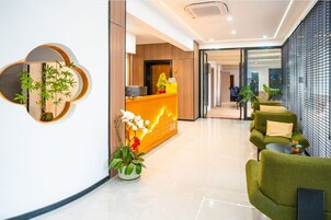 Zona de recepción de un hotel, con mostrador de recepción, área de estar y un diseño interior moderno.