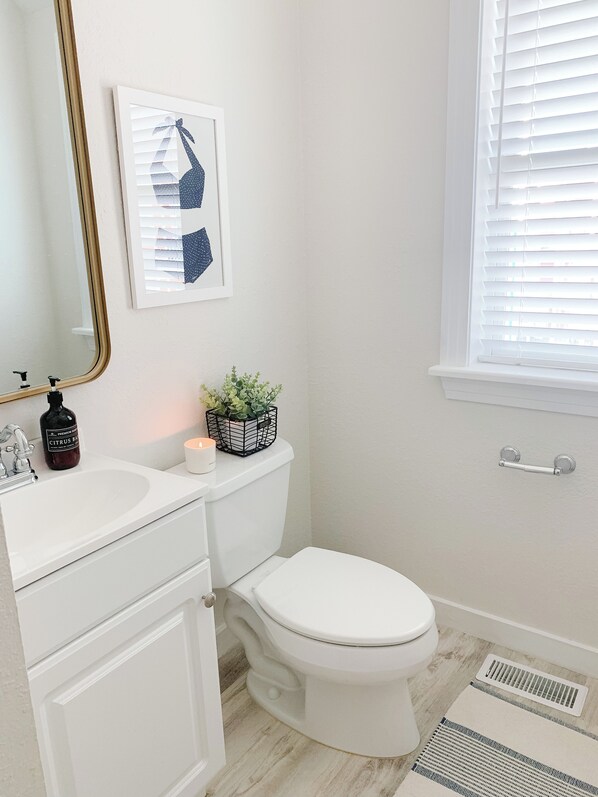 A bathroom with a white sink, toilet, and a window with blinds.