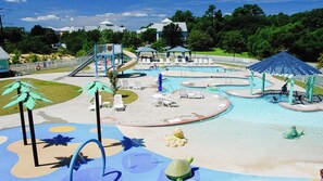 A swimming pool area with multiple pools, lounge chairs, and a water slide.