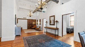 Una camera spaziosa con un ampio pavimento in legno, un tappeto blu decorato, una panca in legno e un lampadario.