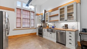 Una cucina moderna con mobili bianchi, elettrodomestici in acciaio inossidabile e un piano di lavoro in legno.