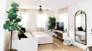 A modern living room with a sofa, TV, and large mirror. - MainCasa- Plunge Pool+Dog Run (St. Petersburg)