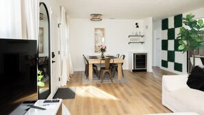 A modern hotel room with a flat-screen TV, a sofa, a dining area with a table and chairs, and a checkered wall. - MainCasa- Plunge Pool+Dog Run (St. Petersburg)