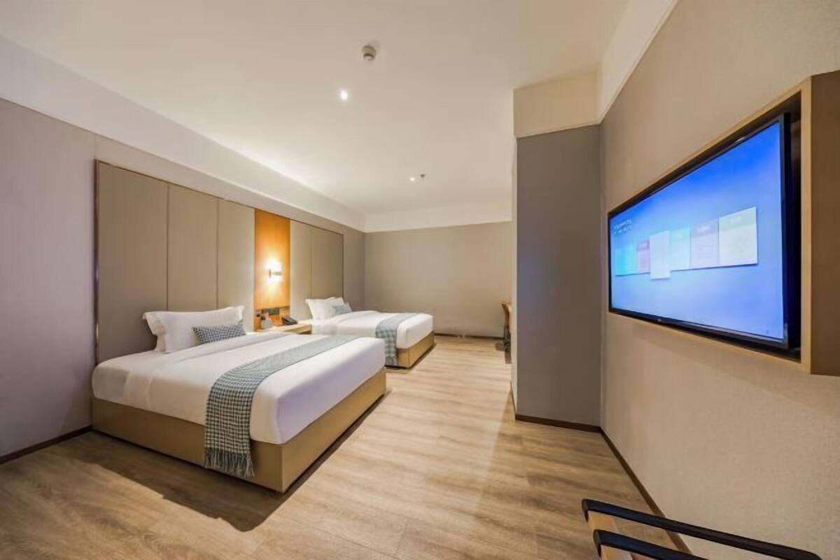 Une chambre d’hôtel avec deux lits, un téléviseur à écran plat et un plancher en bois.