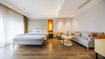 Ein modernes Hotelzimmer mit Bett, Sofa, Ohrensessel und kleinem Tisch.