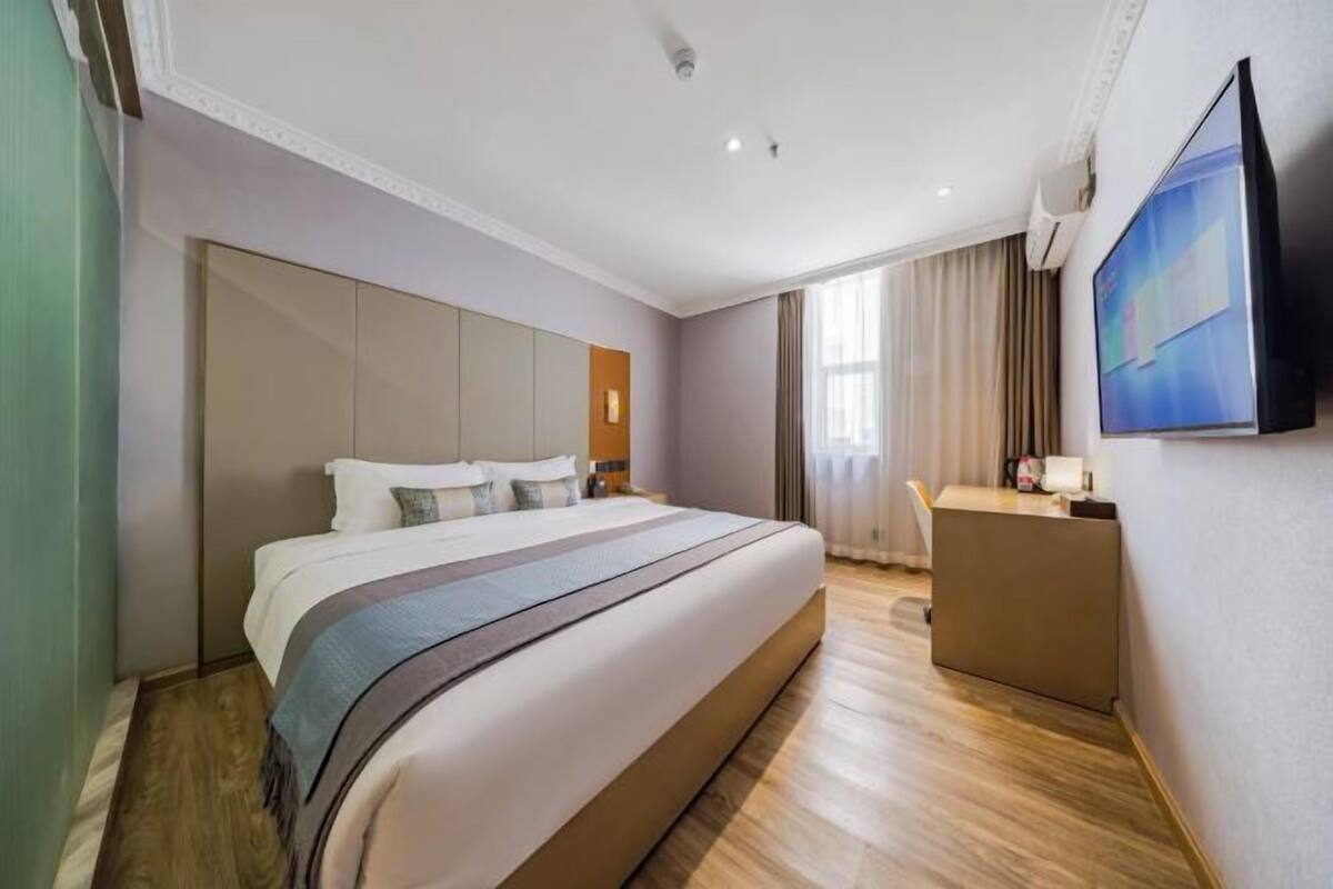Une chambre d’hôtel avec un grand lit, un bureau et un téléviseur à écran plat.