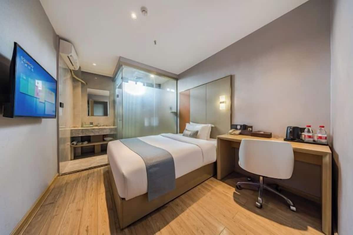 Une chambre d’hôtel moderne équipée d’un lit, d’un bureau, d’une chaise et d’un grand miroir.