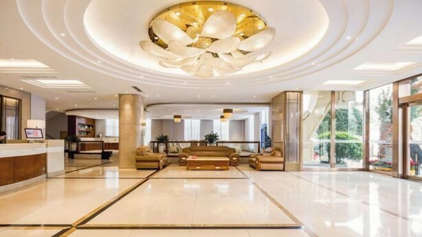 En rummelig lobby med en moderne lysekrone, en reception og et siddeområde med sofaer.
