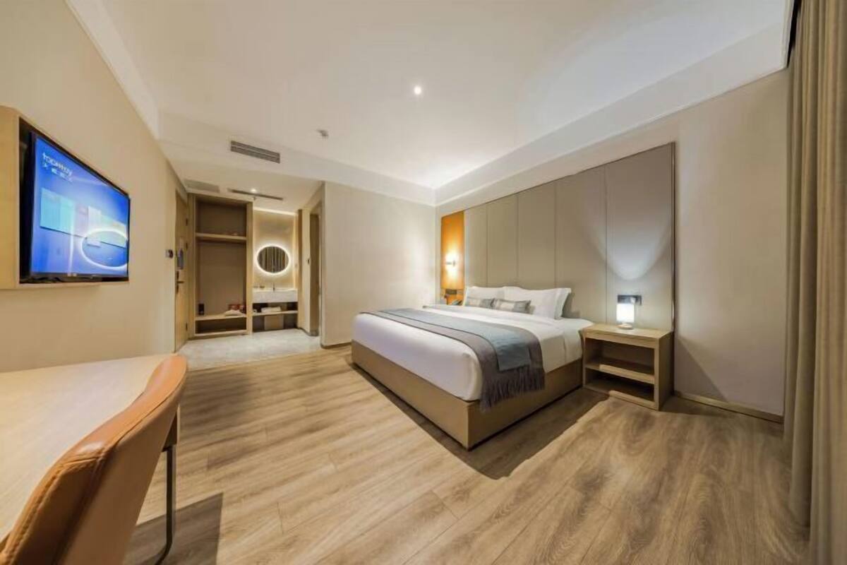 Une chambre d’hôtel comprenant un lit, des tables de chevet, une télévision, un bureau et une armoire.
