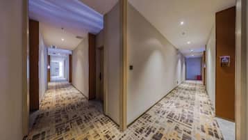 Pasillo de hotel con alfombra estampada, puertas de madera y un cartel que indica la habitación 610.