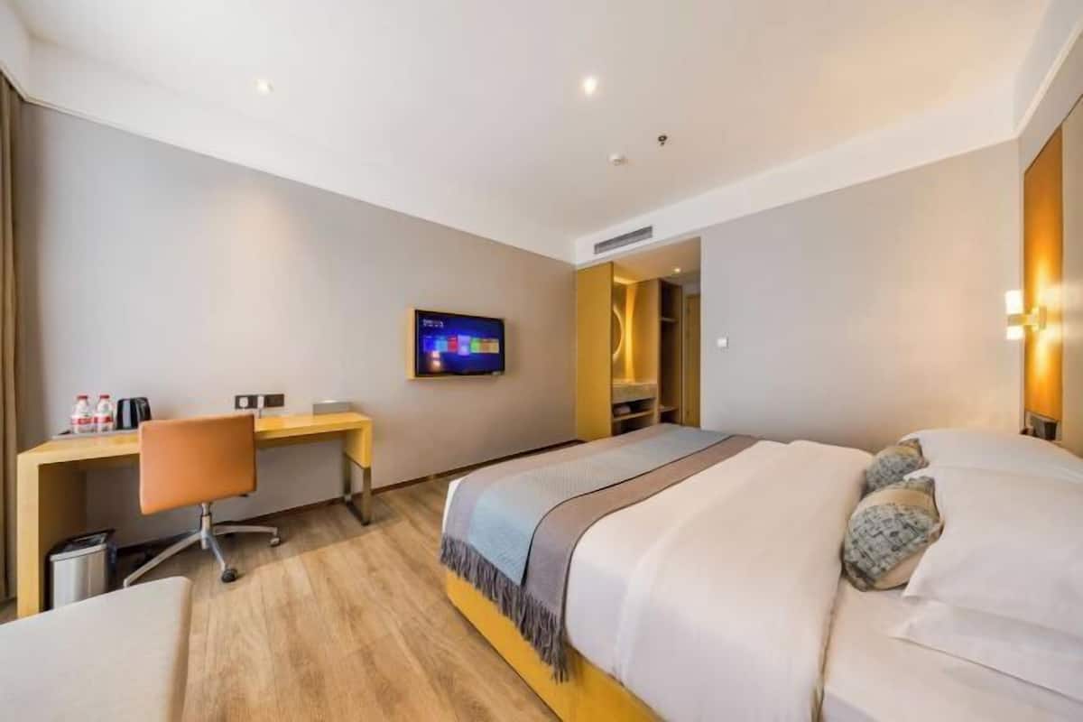 Une chambre d’hôtel moderne équipée d’un lit, d’un bureau, d’une chaise, d’une télévision et d’une salle de bain.