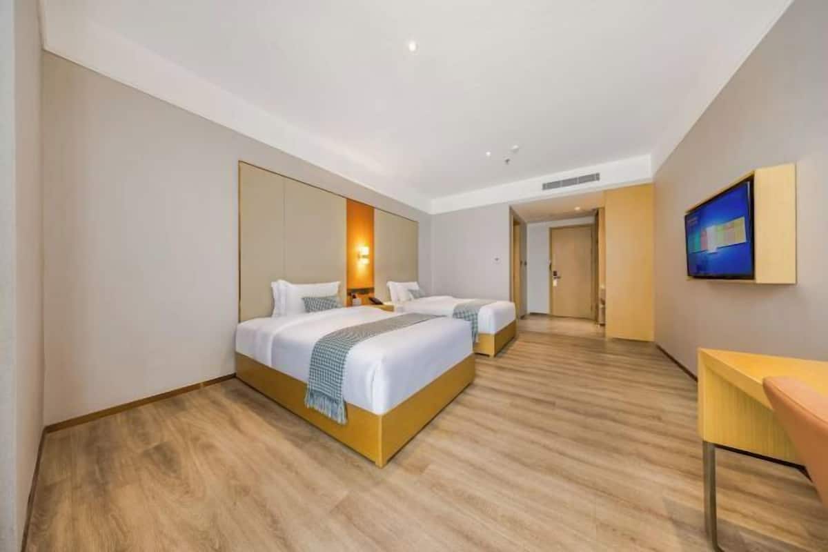 Une chambre d’hôtel avec deux lits, un grand miroir, une télévision et un plancher en bois.