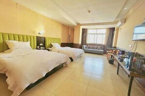 A hotel room with two beds, a sofa, a TV, and a table with bottles. - Orange Hotel Zhoukou (Zhoukou)