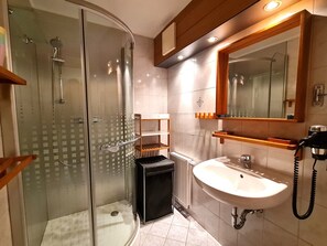A modern bathroom with a glass-enclosed shower, a white sink, and a wooden vanity.