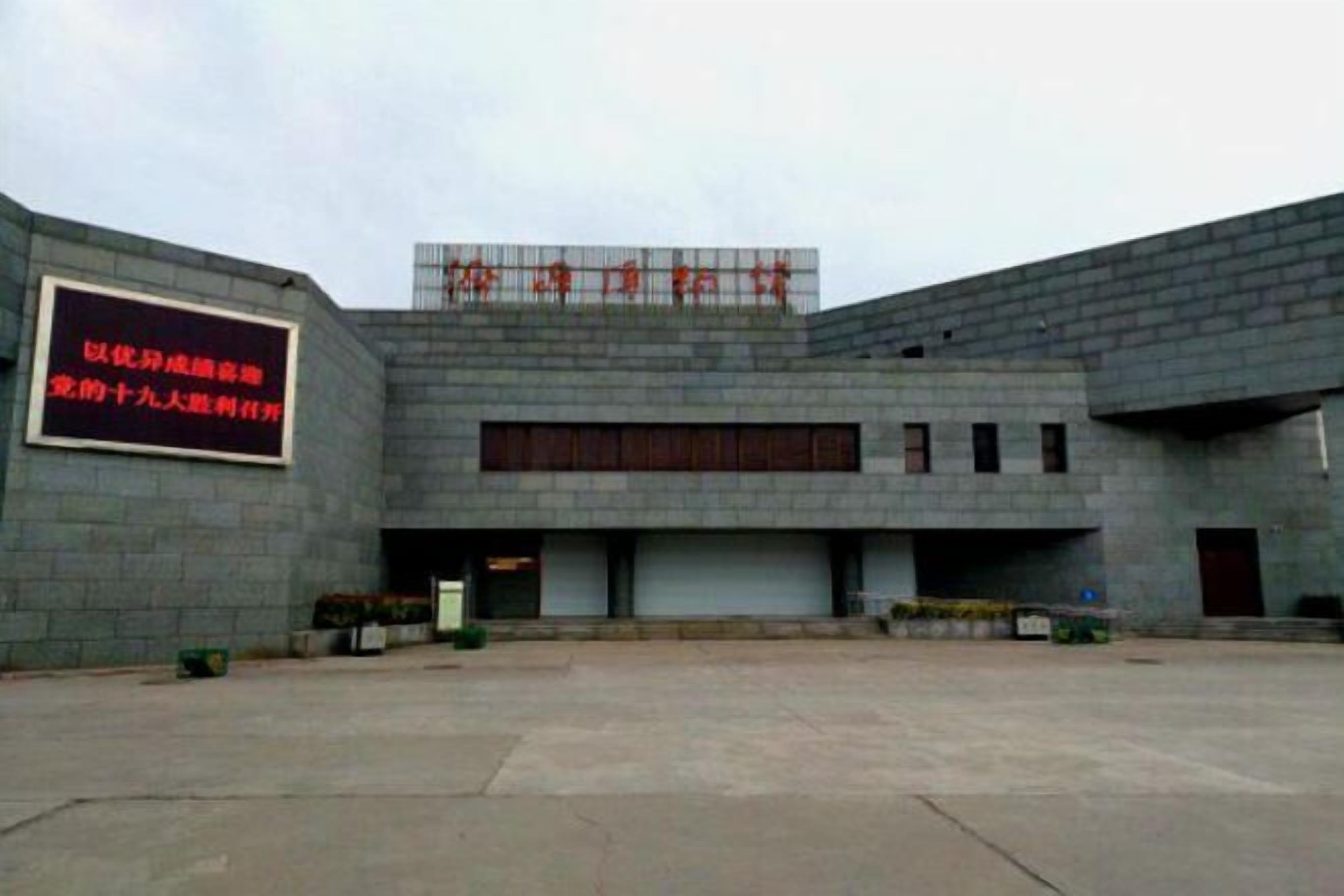 A modern building with a large sign on the left and a series of windows on the upper level.