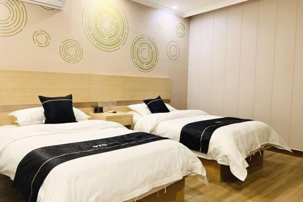 A hotel room with two beds, a wooden headboard, and a wall with circular patterns.
