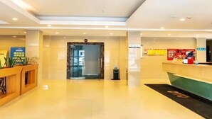 A modern hotel lobby with a reception desk, a glass door entrance, and a clean, tiled floor. - Light Living City Preferred Hotel (RT-Mart) (Jiyuan)