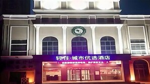 A hotel facade with a prominent clock and illuminated signage. - Light Living City Preferred Hotel (RT-Mart) (Jiyuan)