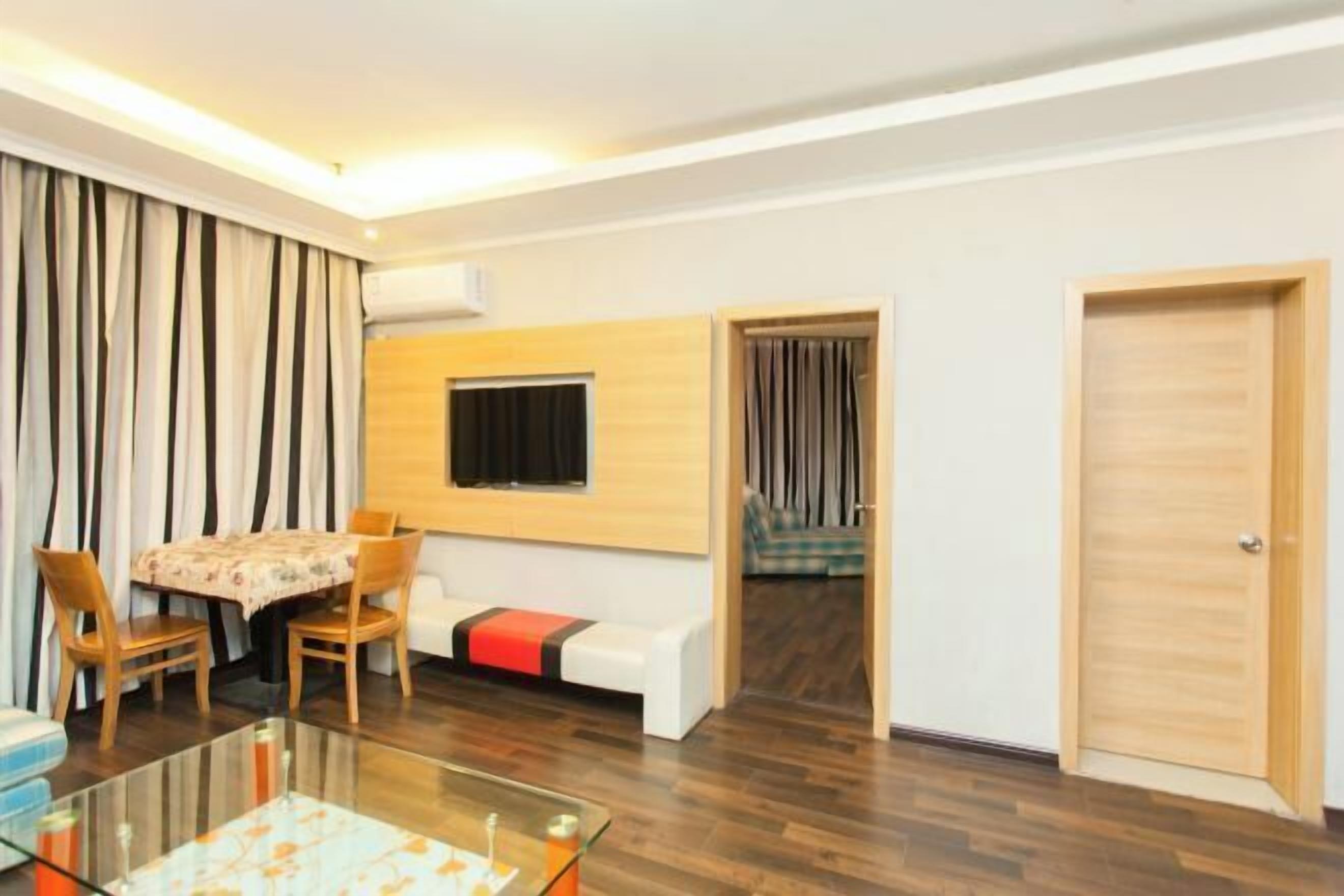 Ein modernes Wohnzimmer mit einem Glastisch, einer Couch, einem Esstisch mit Stühlen und einer Holzwandverkleidung.