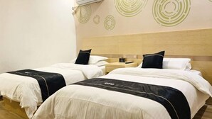A hotel room with two beds, a wooden headboard, and a wall with circular patterns. - Light Living City Preferred Hotel (RT-Mart) (Jiyuan)
