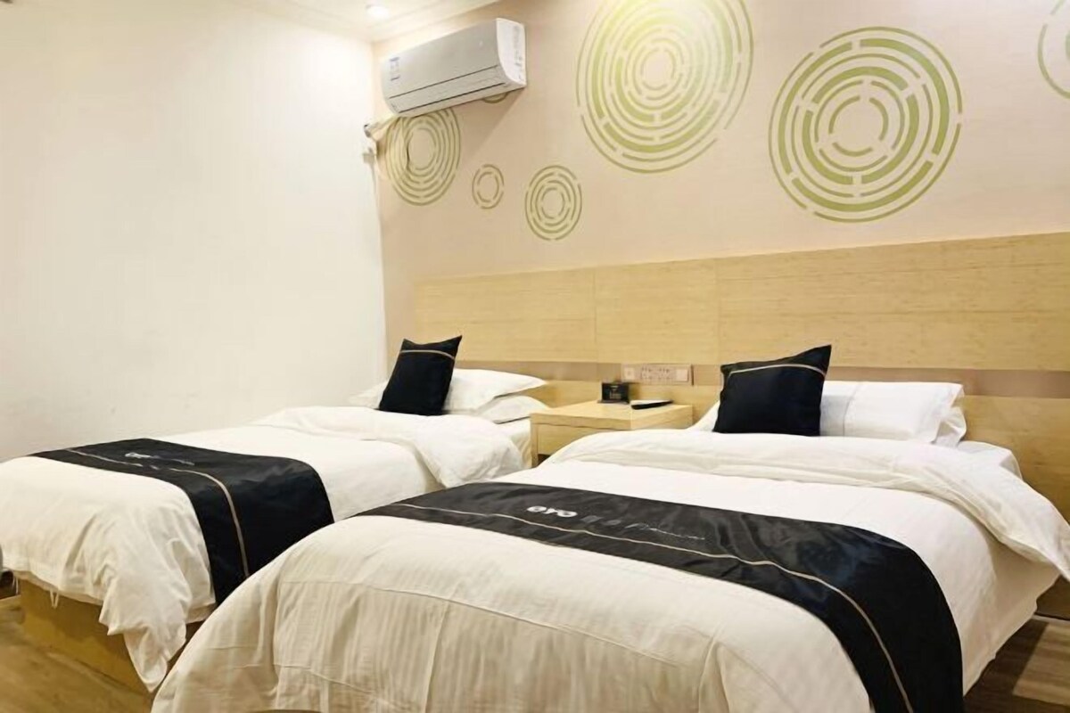 A hotel room with two beds, a wooden headboard, and a wall with circular patterns.