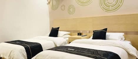 A hotel room with two beds, a wooden headboard, and a wall with circular patterns.
