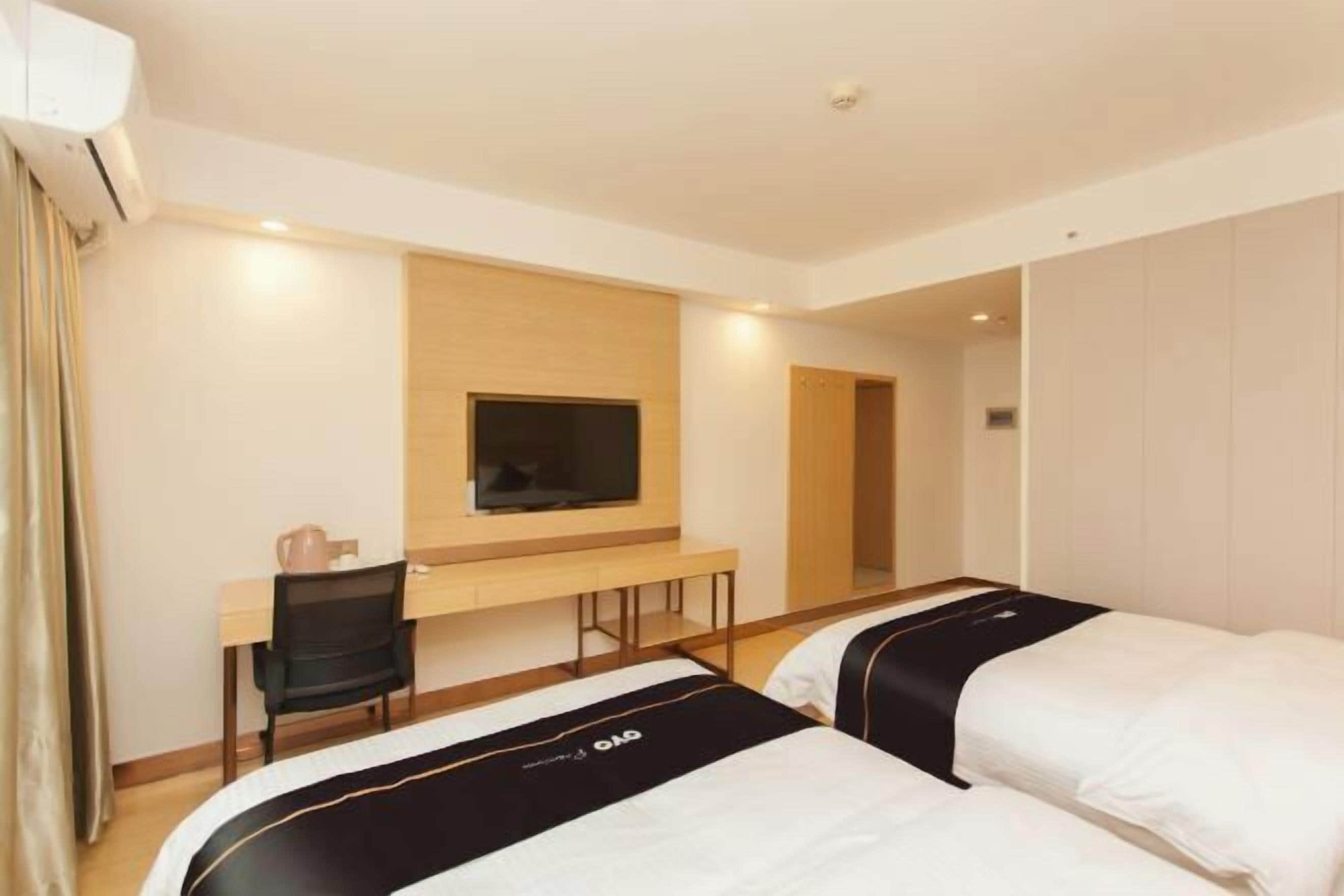 Une chambre d’hôtel comprenant un lit, un bureau, une chaise, une télévision et une armoire.