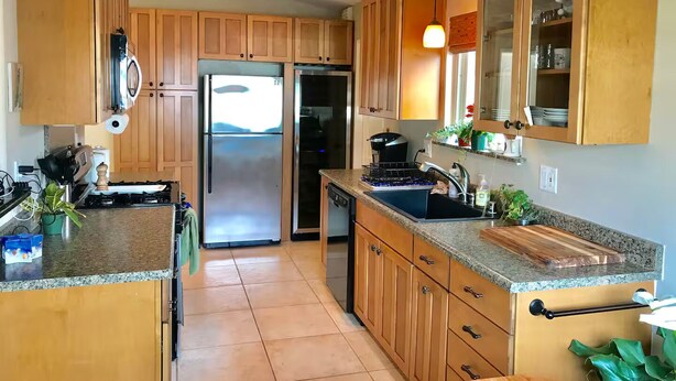 A modern kitchen with wooden cabinets, stainless steel appliances, granite countertops, and a view of the outdoors. - Central Encinitas, 1.4 Miles from Beach (Encinitas)