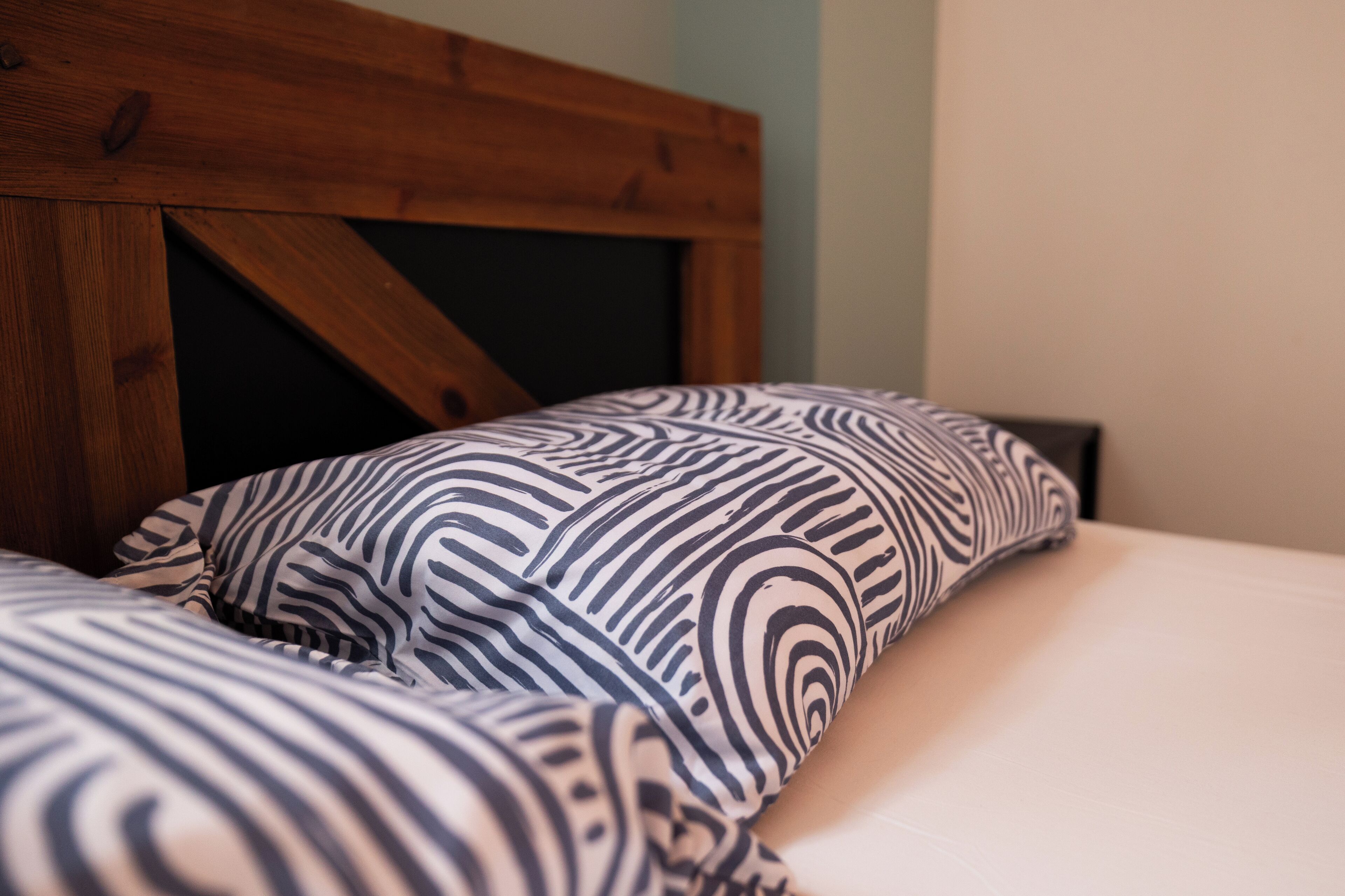 A bed with a patterned pillow and a wooden headboard.