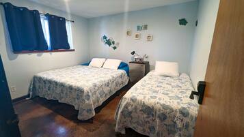 Una habitación con dos camas, un escritorio pequeño y una ventana con cortinas.