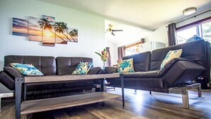 A modern living room with a sofa set, a coffee table, and a wall-mounted TV. - Gods Peace Of Maui (Makawao)