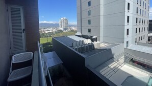A modern building with a flat roof, air conditioning units, and a view of a cityscape.