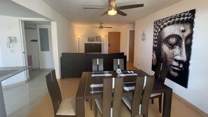A dining area with a table and chairs, a ceiling fan, and a large artwork on the wall.