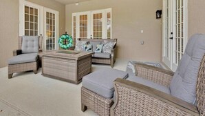Ein überdachter Patio-Bereich mit Korbmöbeln, Deckenventilator und dekorativem Kranz.