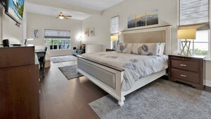Ein Schlafzimmer mit einem großen Bett, einem Schreibtisch und einem Deckenventilator.