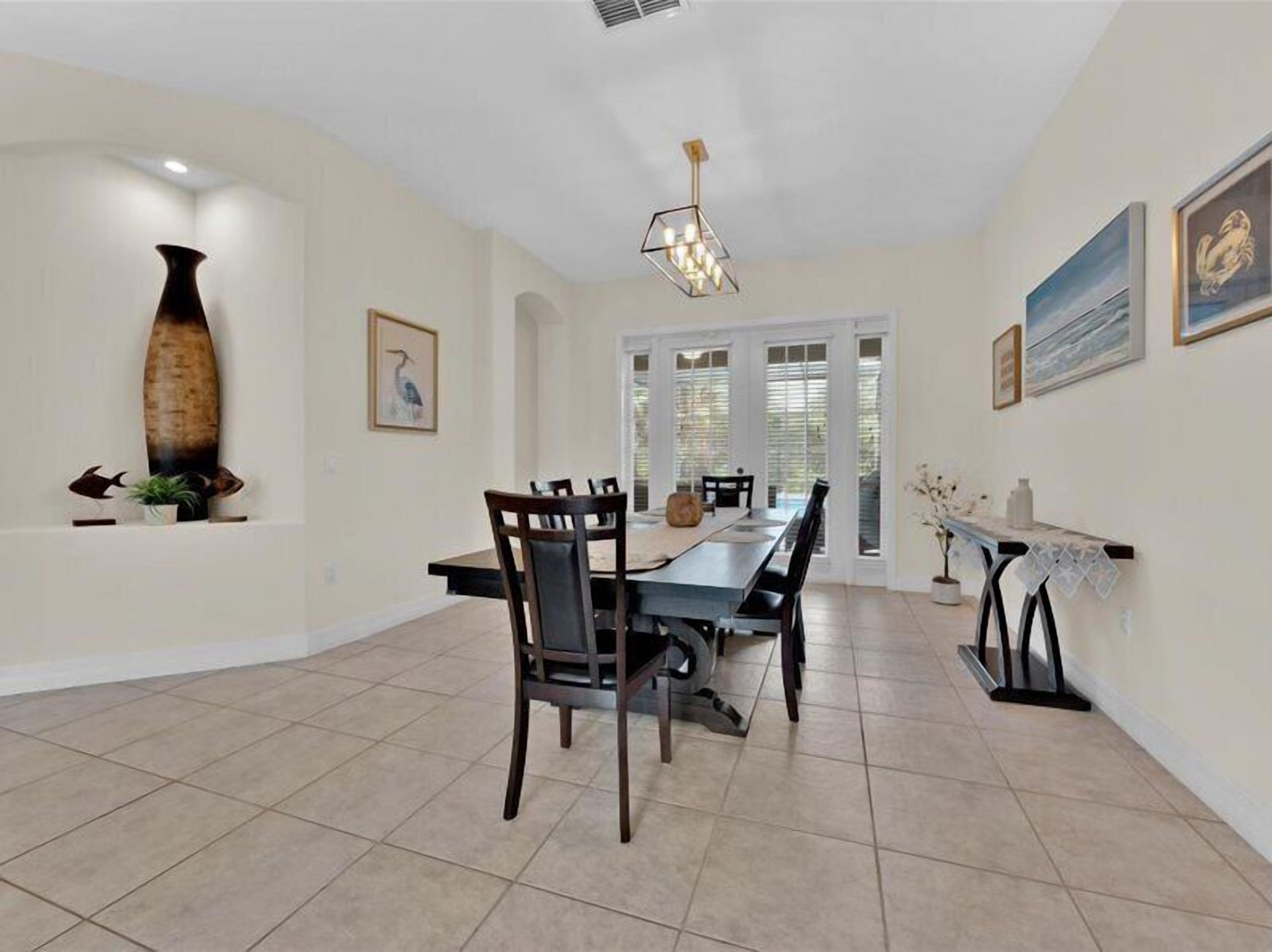 A spacious dining area with a long table, chairs, and a chandelier.