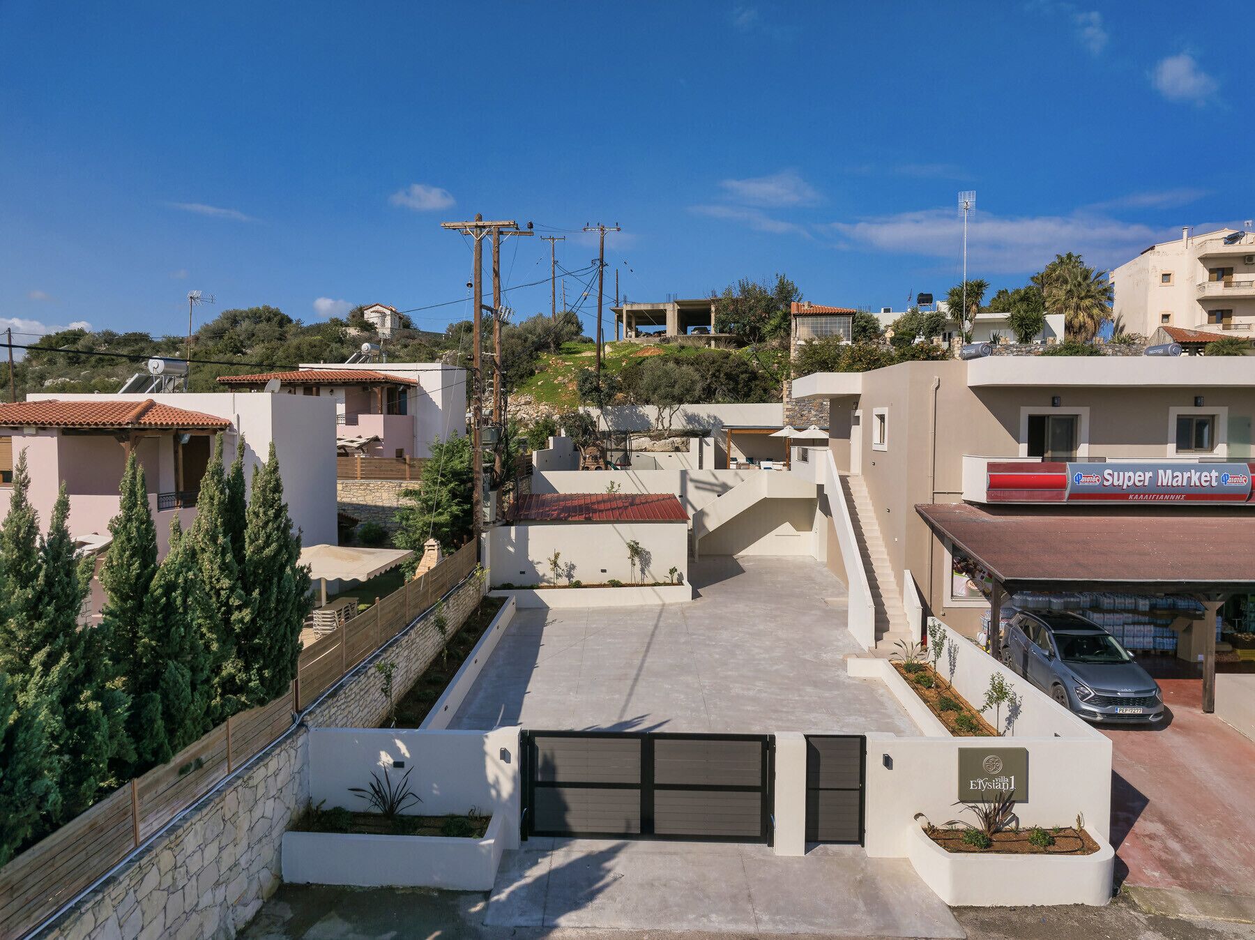 A residential area with modern houses, a gated entrance, and a Super Market sign.