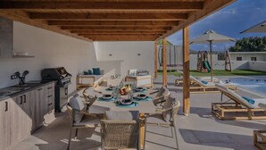 Eine Terrassengruppe im Freien mit Esstisch und Platz für vier Personen, umgeben von Korbstühlen.